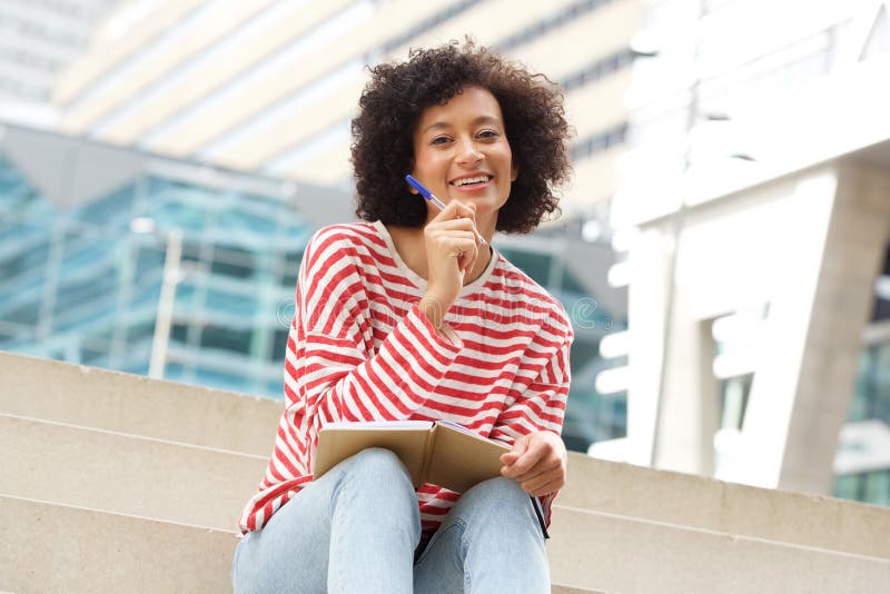 Attractive older woman sitting outdoors on steps with book and pen stock photo Attractive older woman sitting outdoors on steps with book and pen stock photo