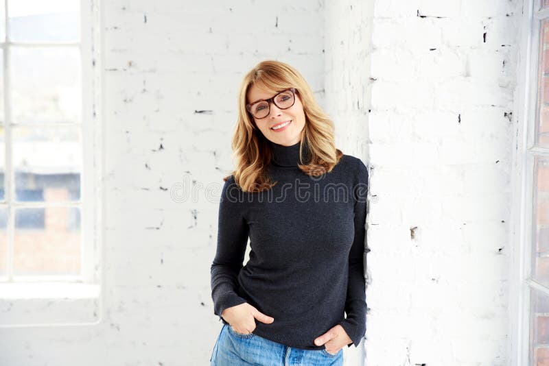 Portrait of attractive woman wearing roll neck sweater and jeans while looking at camera and smiling stock photography Portrait of attractive woman wearing roll neck sweater and jeans while looking at camera and smiling stock photography