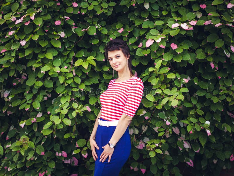 Portrait of an attractive young sensual woman on a background of ivy wall with green leaves. stock images