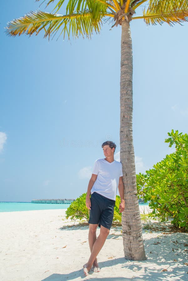 Portrait of attractive young sexy man wearing t-shirt and shorts at tropical beach at island luxury resort royalty free stock photography Portrait of attractive young sexy man wearing t-shirt and shorts at tropical beach at island luxury resort royalty free stock photography