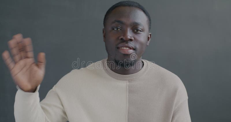 Portrait au mouvement lent d'un Africain Américain heureux brandissant la main souriant sur fond noir banque de vidéos