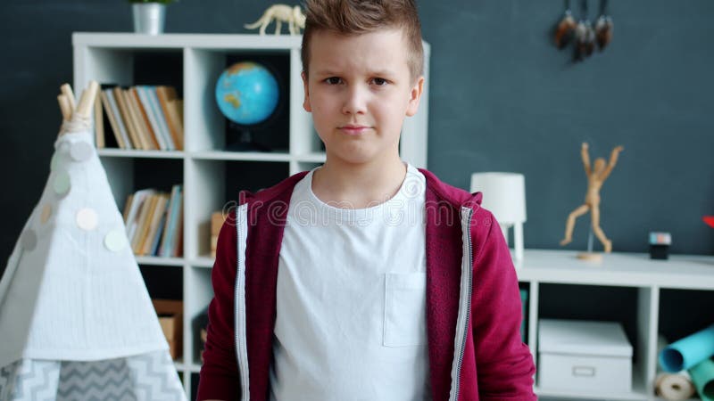 Portrait au ralenti d'un enfant sérieux debout à l'intérieur de l'appartement regardant la caméra banque de vidéos