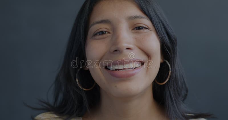 Portrait au ralenti d'une femme hispanique joyeuse qui rit en regardant la caméra sur fond noir banque de vidéos