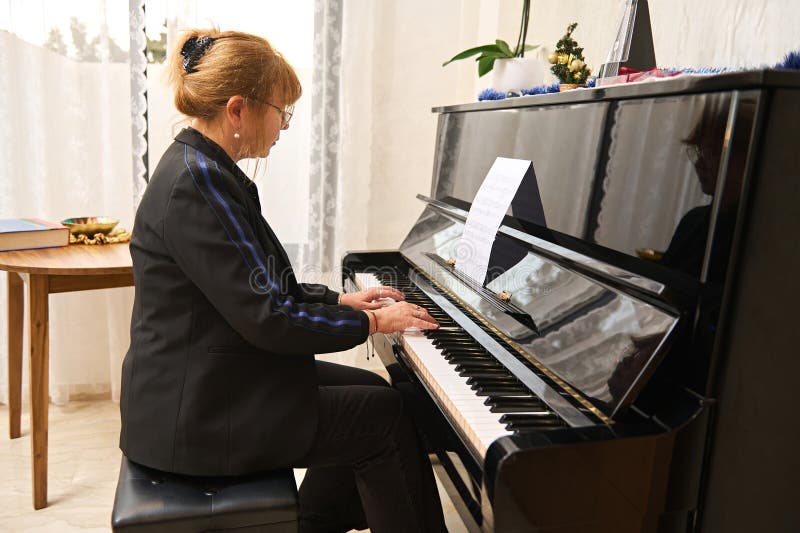 Portrait authentique et confiant d'une asiatique mature en tenue décontractée jouant du piano et chantant à la maison image libre de droits