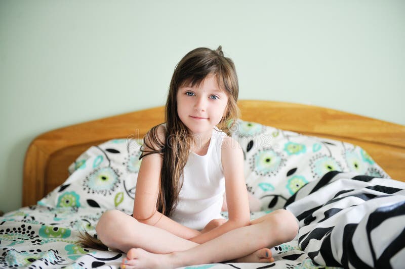 Portrait of awaken little girl sitting in bed