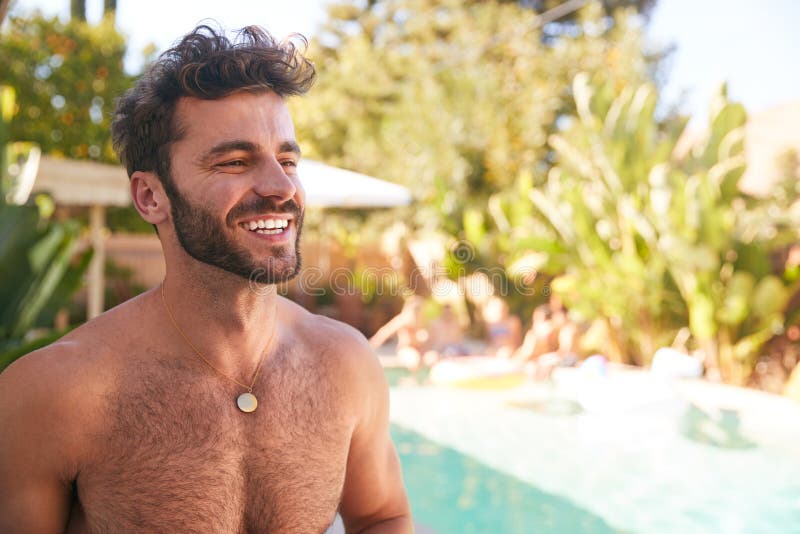 Portrait Of Bare Chested Hispanic Man Outdoors With Friends Enjoying Summer Pool Party