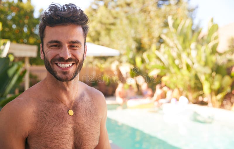 Portrait Of Bare Chested Hispanic Man Outdoors With Friends Enjoying Summer Pool Party