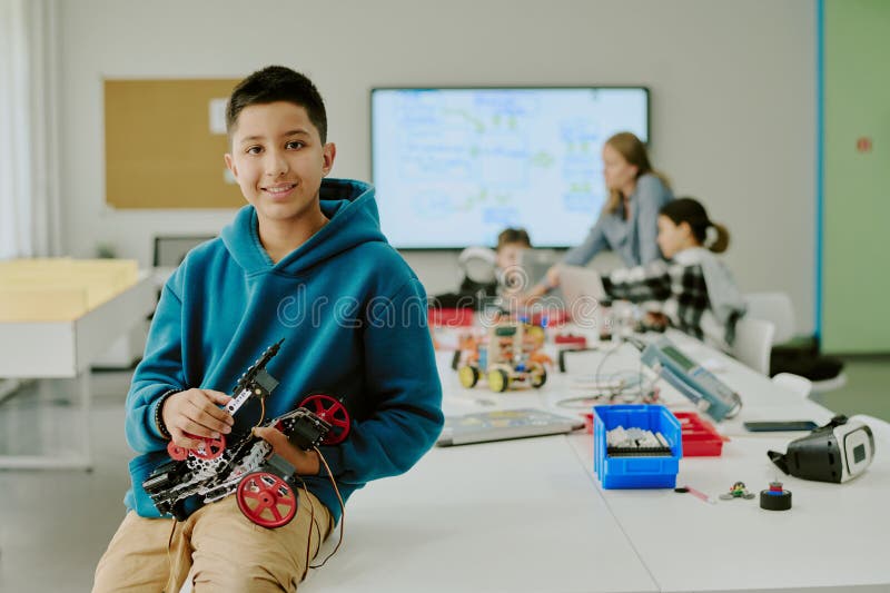 Smiling Boy with Robot Sitting on Desk royalty free stock image