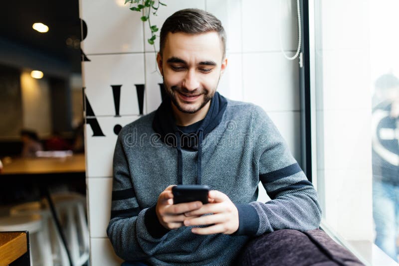 Portrait of bearded man with mobile phone in cafe