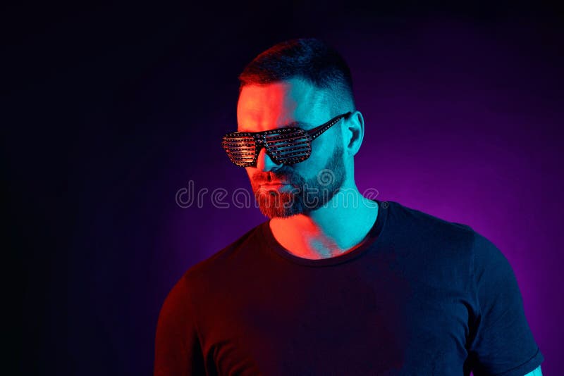 Portrait of a bearded serious man at studio. High Fashion male model in colorful bright neon lights posing on black royalty free stock photo Portrait of a bearded serious man at studio. High Fashion male model in colorful bright neon lights posing on black royalty free stock photo