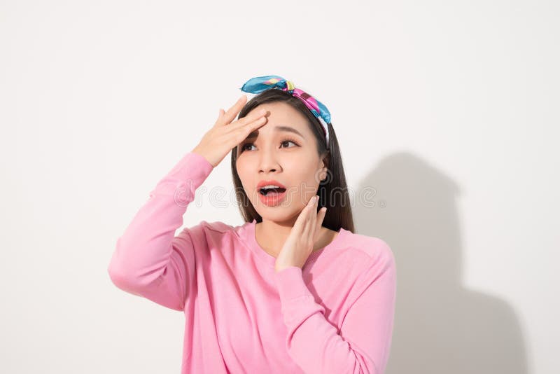 Portrait of a beautiful Asian girl  covering face by hand of bright sun light. Woman in a pink dress protecting her face from