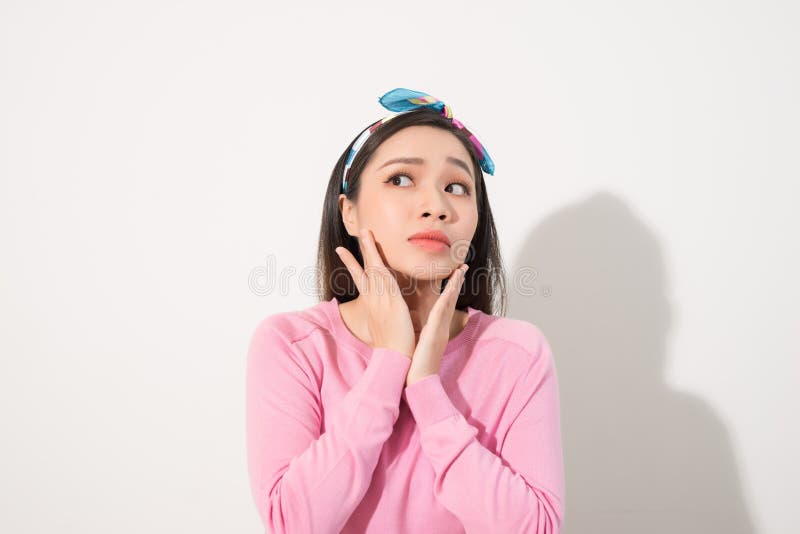 Portrait of a beautiful Asian girl  covering face by hand of bright sun light. Woman in a pink dress protecting her face from