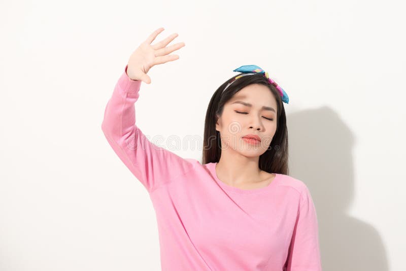 Portrait of a beautiful Asian girl covering face by hand of bright sun light. woman in a pink dress protecting her face from solar