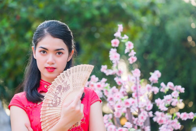 Portrait beautiful Asian girl wearing Cheongsam red dress hold fan