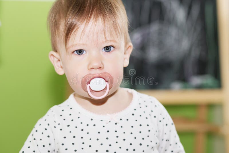 Portrait of a Beautiful Baby with Pacifier in the Mouth Stock Photo