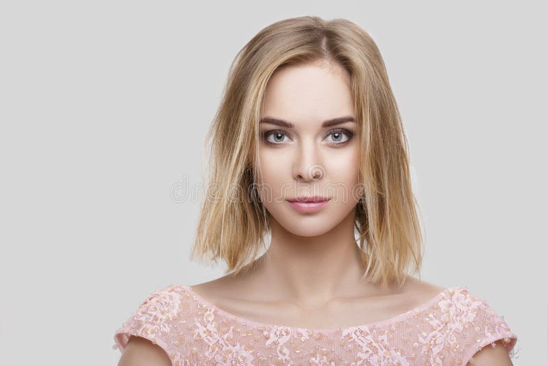 Portrait of beautiful blond woman with short hair in pink cocktail dress on grey background stock photography Portrait of beautiful blond woman with short hair in pink cocktail dress on grey background stock photography