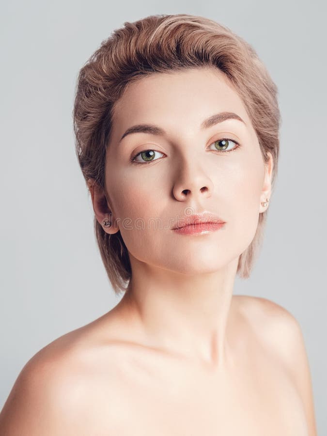 Portrait of a Beautiful Blonde with Short Hair and Green Eyes on a Gray