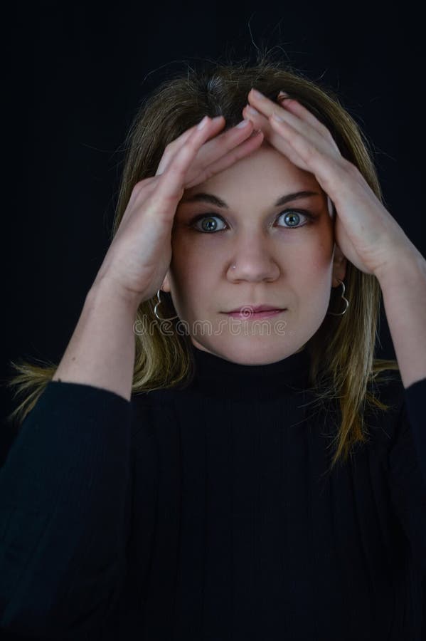 Portrait Of A Beautiful Blonde Woman With Her Hands On Her Forehead Looking Through Her Fingers