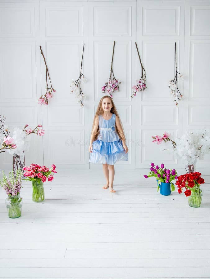 Portrait of a beautiful blue-eyed girl, a little girl among spring flowers in a bright room