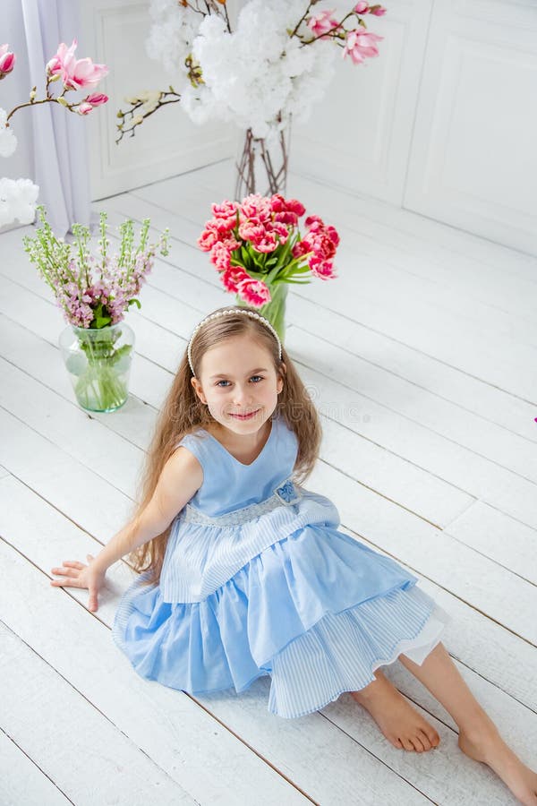 Portrait of a beautiful blue-eyed girl, a little girl among spring flowers in a bright room