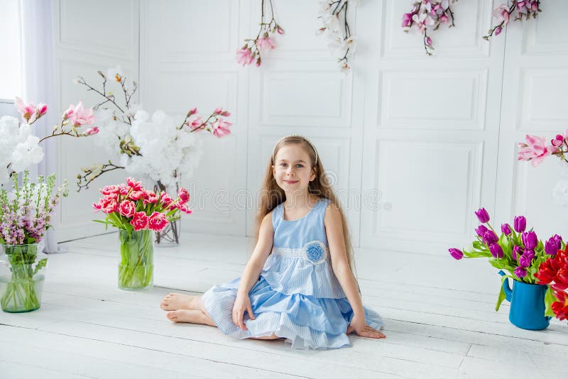 Portrait of a beautiful blue-eyed girl, a little girl among spring flowers in a bright room