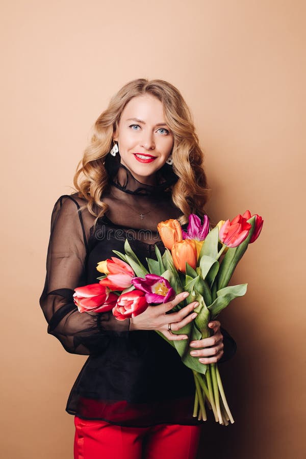 Portrait of beautiful fashion woman posing with colorful tulips having positive emotion