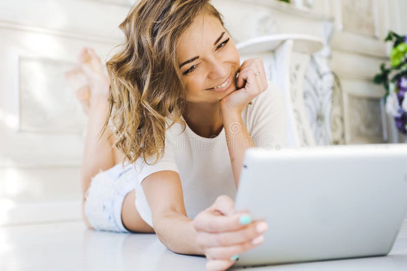 Portrait of a beautiful girl gentle, cute young, lying on the floor, with laptop posing