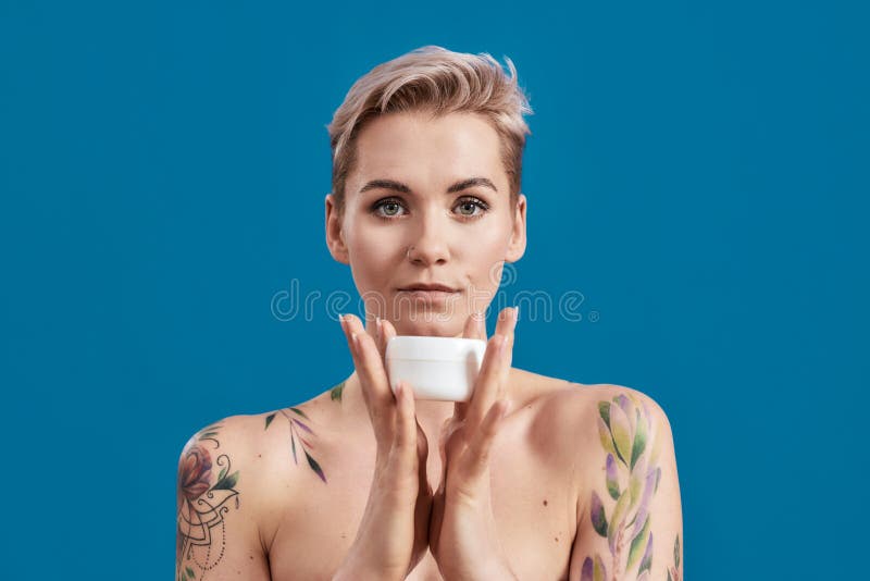 Portrait Of Beautiful Half Naked Tattooed Woman With Short Hair Holding White Plastic Jar Of