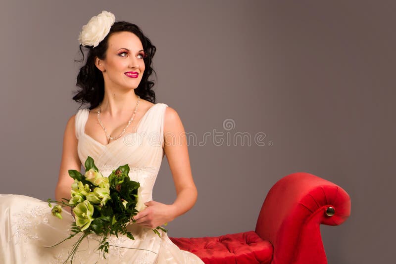 Portrait of a beautiful happy bride on red sofa