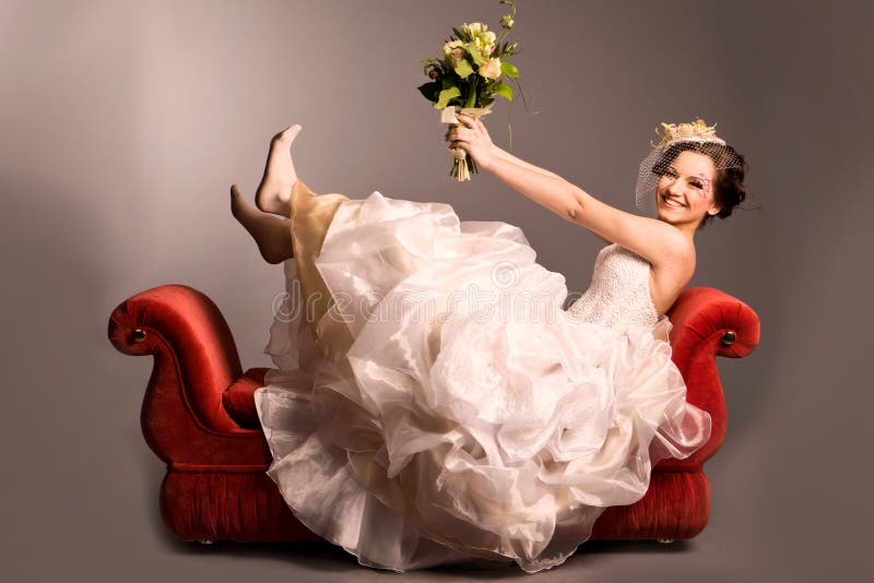 Portrait of a beautiful happy bride on red sofa