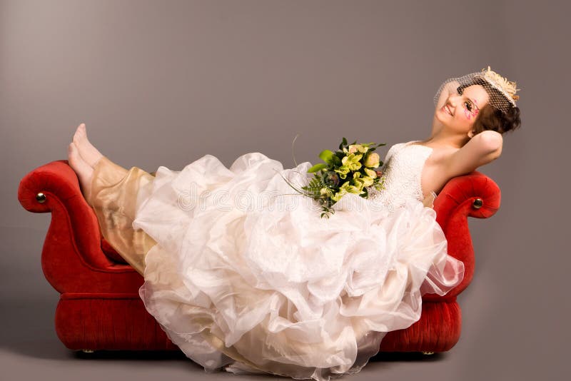 Portrait of a beautiful happy bride on red sofa