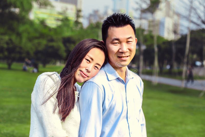 Portrait of beautiful happy Chinese couple looking at camera together in the Park.