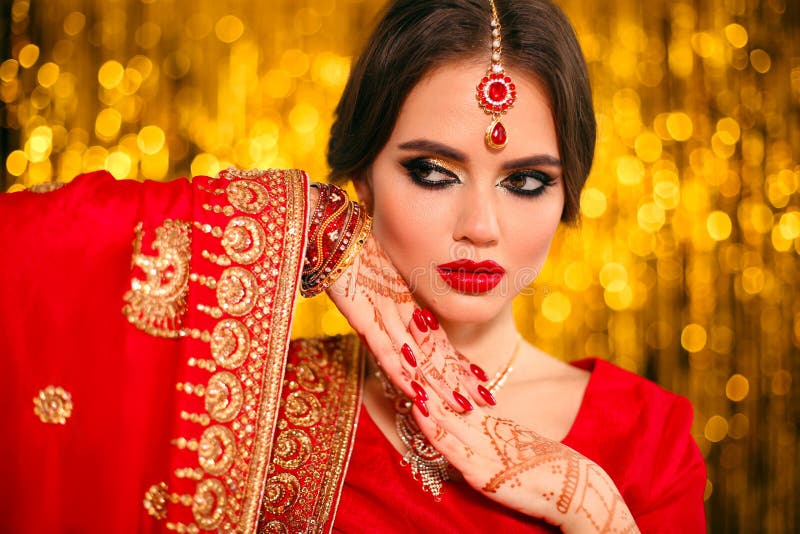 Portrait of beautiful indian girl in red bridal sari over golden bokeh. Young hindu woman model with kundan jewelry. Traditional royalty free stock photography Portrait of beautiful indian girl in red bridal sari over golden bokeh. Young hindu woman model with kundan jewelry. Traditional royalty free stock photography