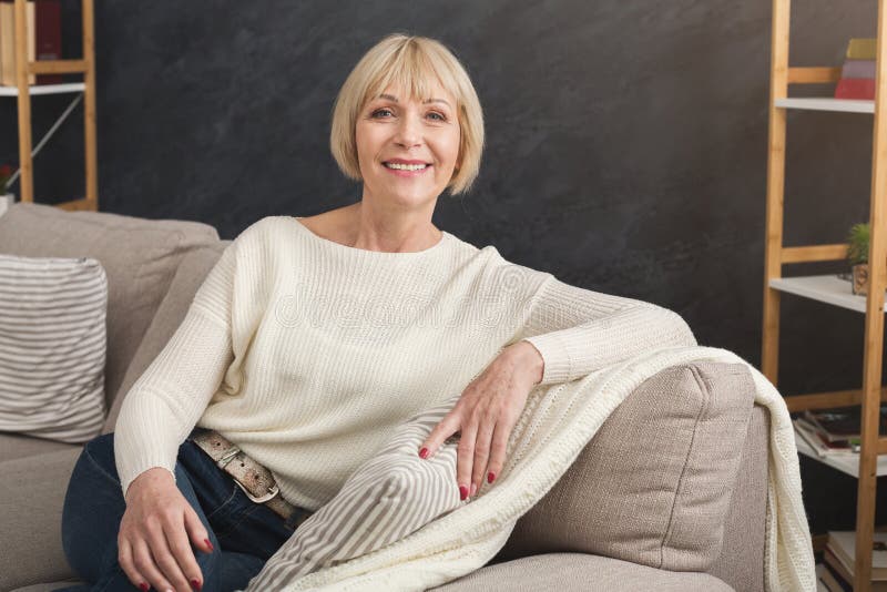 Portrait of beautiful middle aged woman sitting on sofa. 