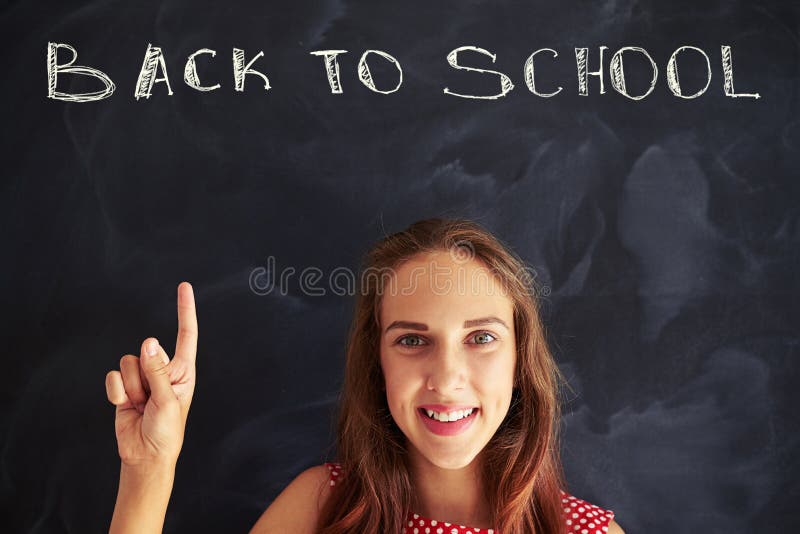 Portrait of beautiful schoolgirl pointing up with forefinger at. Back to school chalk inscription on blackboard royalty free stock photos Portrait of beautiful schoolgirl pointing up with forefinger at. Back to school chalk inscription on blackboard royalty free stock photos