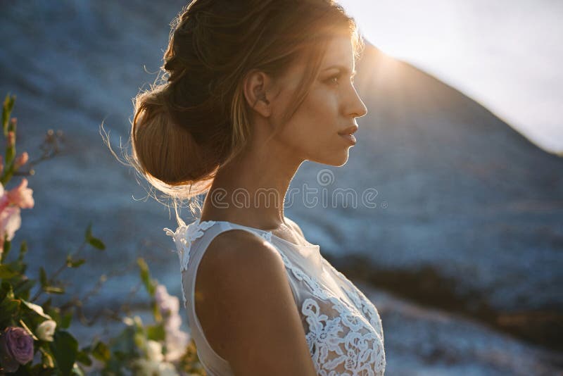 Portrait of beautiful and sensual blonde model girl with modeling stylish hairstyle in fashionable white lace dress posing at the