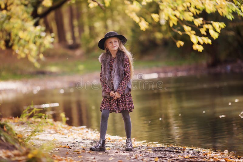 Portrait of a beautiful smiling fashionable girls. Little girl with long hair standing by the pond on a sunny day royalty free stock photography Portrait of a beautiful smiling fashionable girls. Little girl with long hair standing by the pond on a sunny day royalty free stock photography