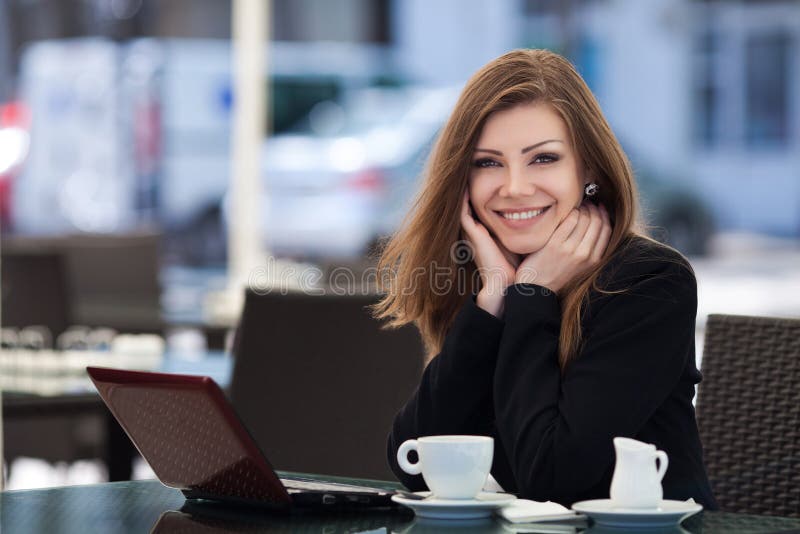 Portrait of beautiful smiling woman sitting in a cafe with laptop outdoor