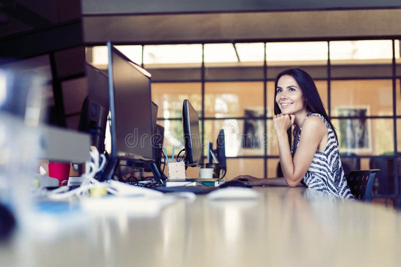 Portrait of beautiful smiling young brunette businesswoman sitting at bright modern work station and typing on computer royalty free stock images Portrait of beautiful smiling young brunette businesswoman sitting at bright modern work station and typing on computer royalty free stock images