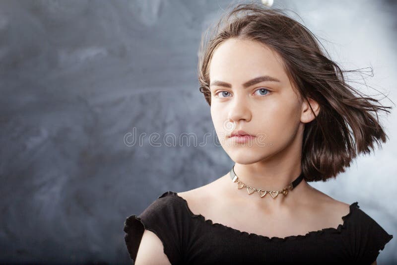 Portrait of beautiful teen girl with fluttering hair. Girl`s face  with wind in hair on black background