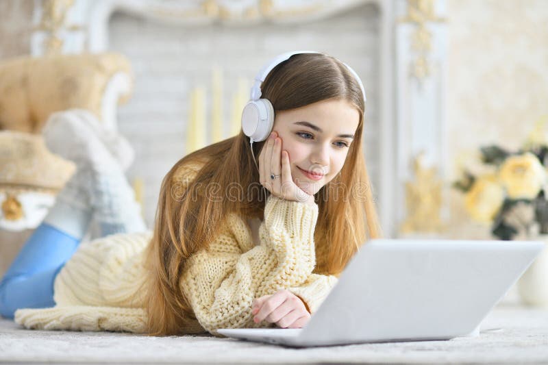 Beautiful teen girl lying on floor and using laptop