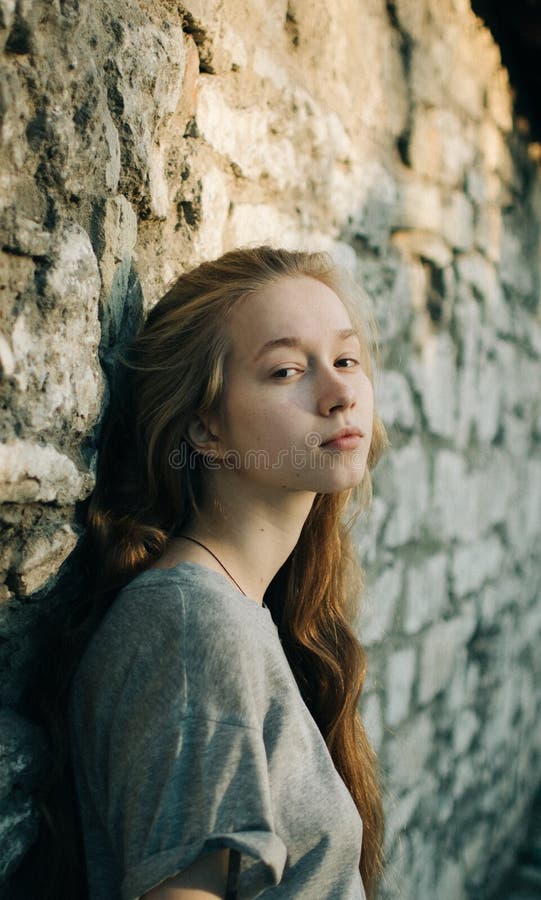 Portrait of beautiful teenager girl leaning on textured stone wall outdoors, looking smiling at camera. stock image Portrait of beautiful teenager girl leaning on textured stone wall outdoors, looking smiling at camera. stock image