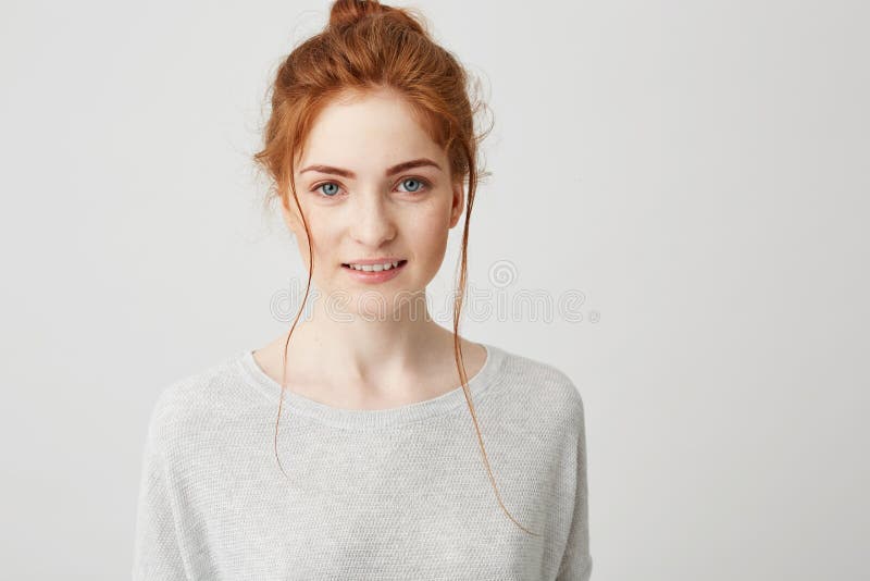 Portrait of beautiful tender ginger girl smiling posing looking at camera over white background.