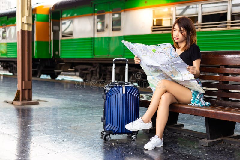 Portrait beautiful traveler woman. Pretty girl is looking a map at a train station. Beautiful woman is planning to go to tourist attraction or tourism location for taking a trip or journey. copy space