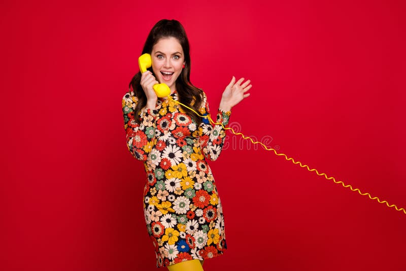 Portrait of beautiful trendy girly girl talking on phone land line discussing news isolated over bright red color