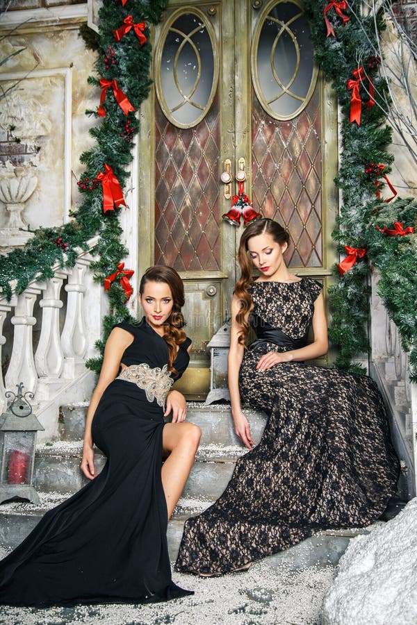 Portrait of beautiful twins young women in gorgeous evening dresses over christmas background royalty free stock image Portrait of beautiful twins young women in gorgeous evening dresses over christmas background royalty free stock image