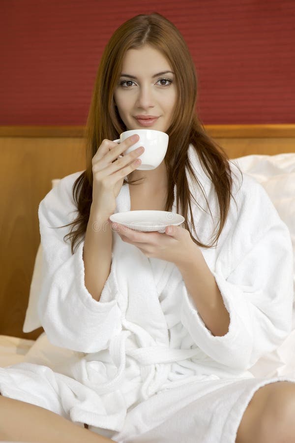 Portrait of beautiful woman with cup on bed
