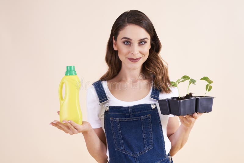 Portrait of beautiful woman holding cucumber seedling and fertilizer royalty free stock photo Portrait of beautiful woman holding cucumber seedling and fertilizer royalty free stock photo