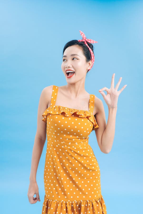 Portrait of a beautiful woman pinup retro style pointing at you smiling laughing isolated blue background wall. Body language