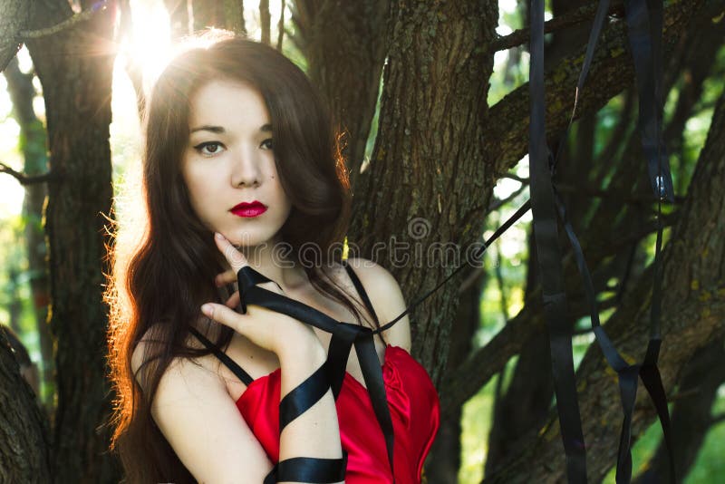 Portrait of beautiful woman in red dress outdoors with black strings